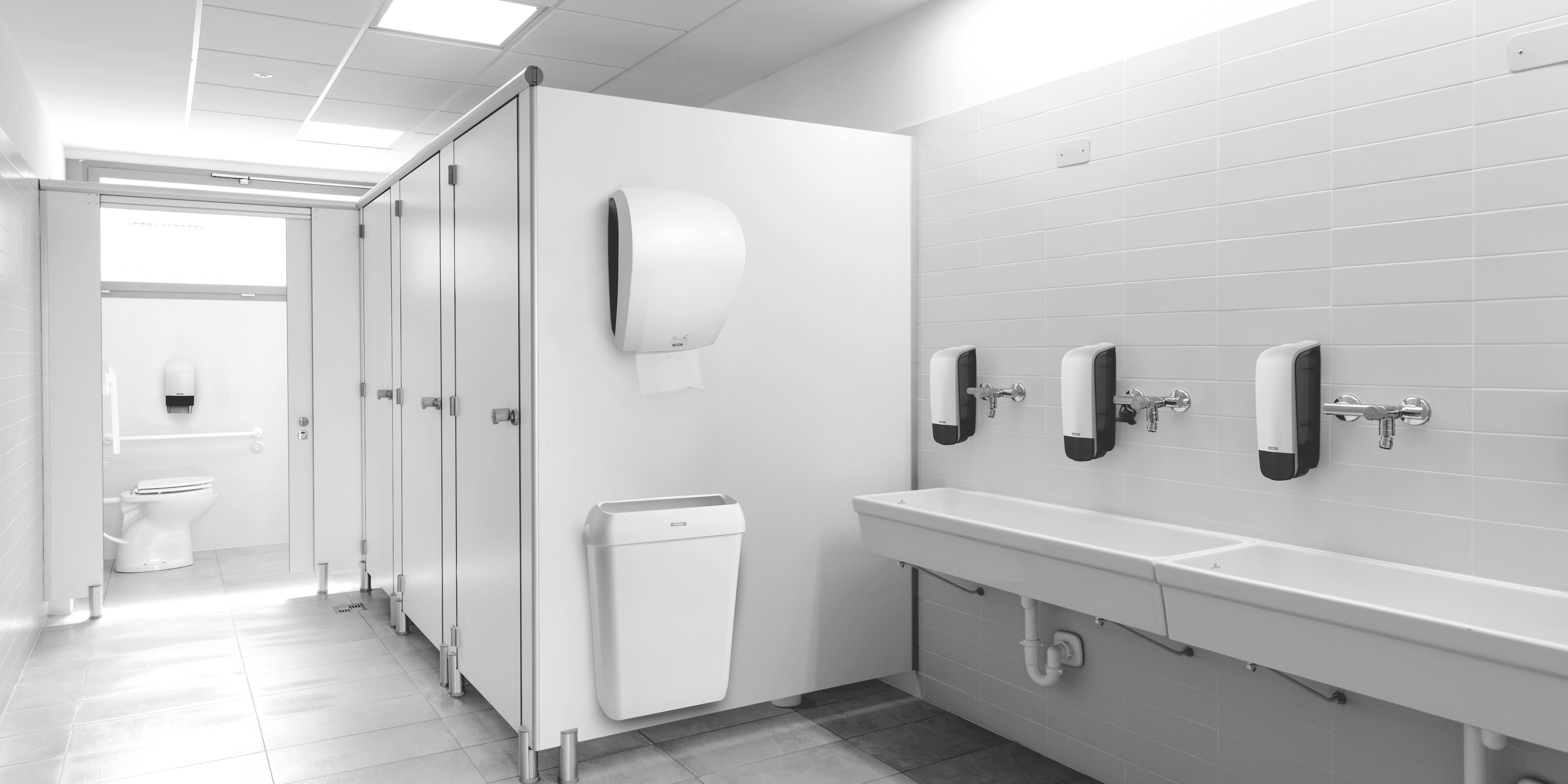Weiße Toilette mit Tork Seifenspender, Mülleimer und Papierhandtuchspender